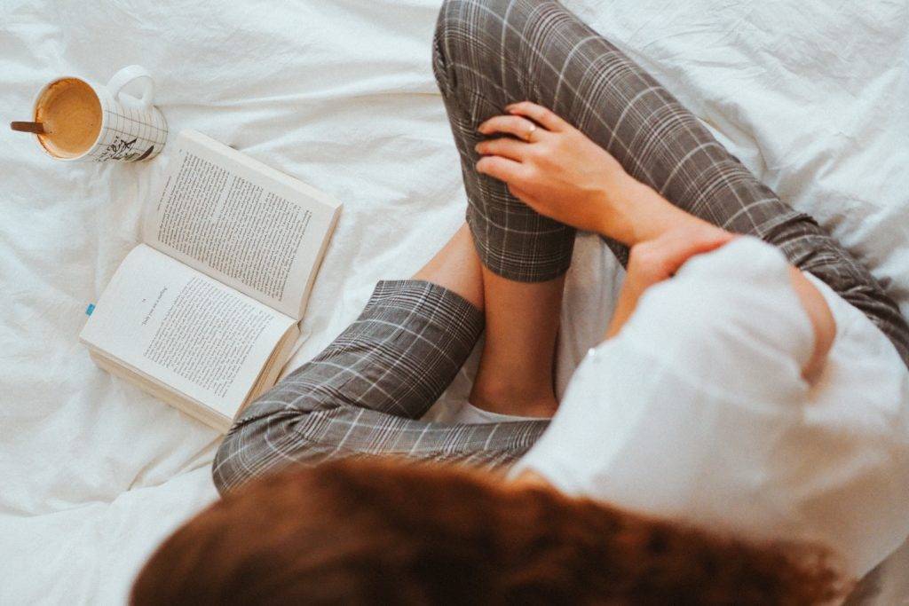 Woman sitting on bed reading 